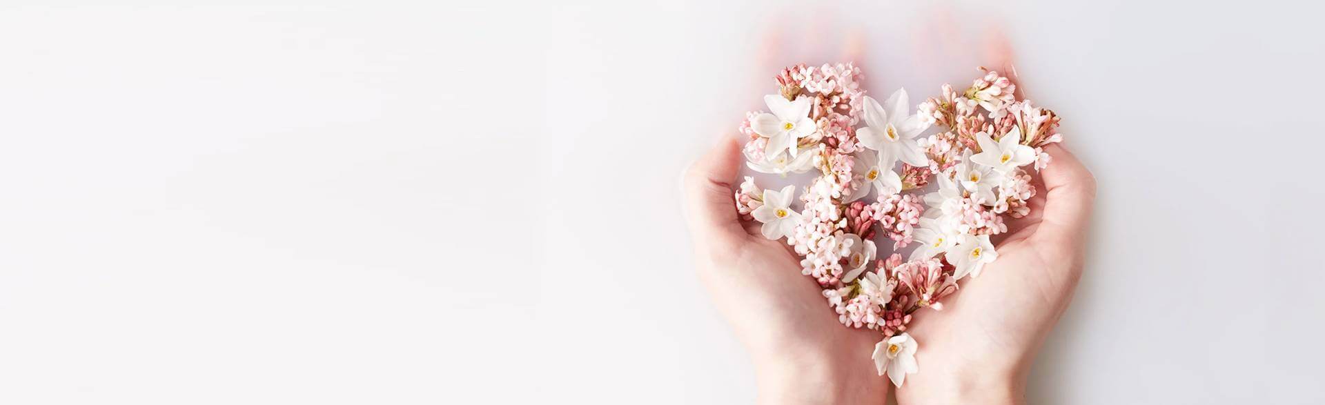 Picture of a woman's hands holding flower petals in a heart shape by Neal's Yard Remedies